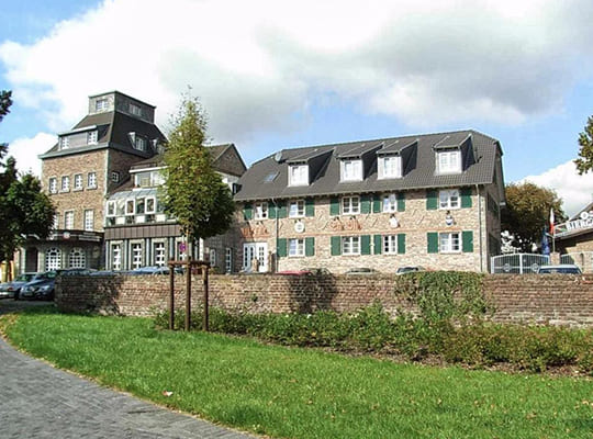 Großes modernisiertes Backsteinhaus vor einer grünen Wiese und Backsteinmauer