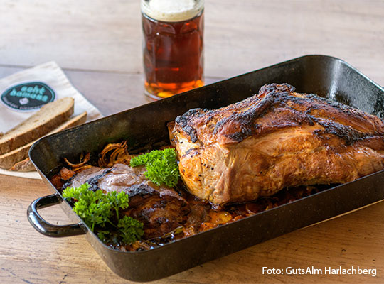 Ein Braten, welcher auf einem Teller liegt mit einem Kühlen Bier, in einem Glas, vor dem Braten