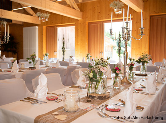 Innenansicht der GutsAlm Harlachberg, von einer großen Tischtafel, mit weißer Tischdecke