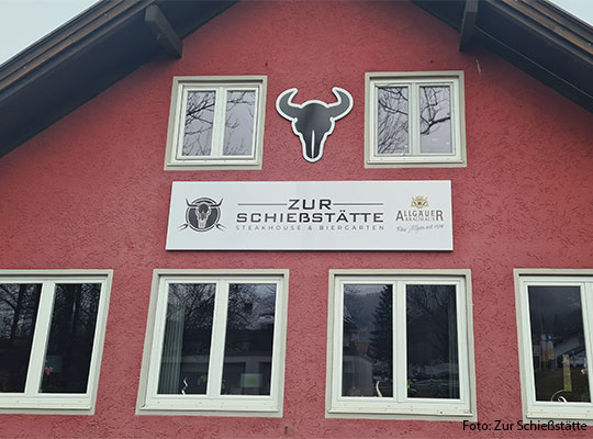 Eine rote Hausfassade mit einem Schild in Form eines Stierkopf 