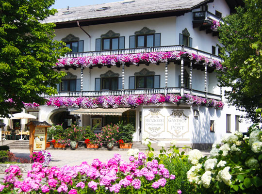 In einer Blumenpracht stehendes uriges Gebäude mit Verzierungen an der Hauswand