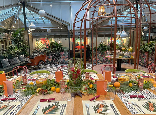 Mit vielen Früchten und Blumen verzierter Speisesaal, im Vordergrund garnierte Tische