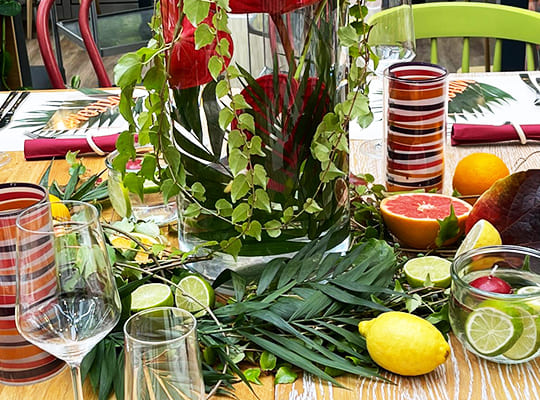 Liebevoll verzierter Tisch mit Pflanzen und Früchten, darin steht das Geschirr