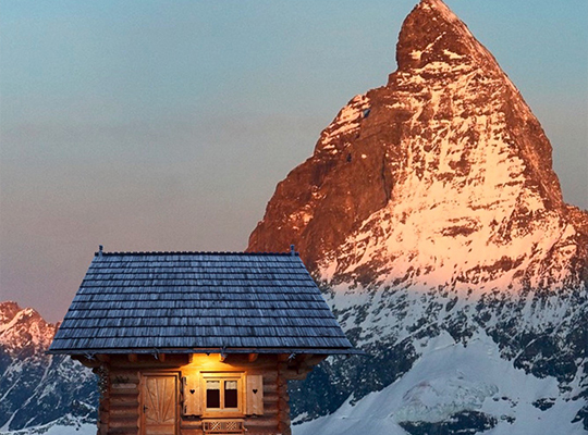 Kleine Holzhütte vor einem Berggipfel