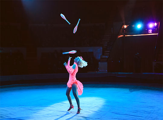 Eine Frau jongliert unter Schwarzlicht in einem leuchtenden Outfit