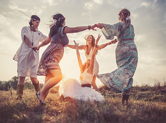 Fünf Hippies tanzen fröhlich auf einer Wiese