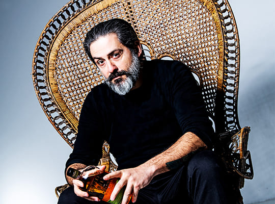 Unser Gin Experte Carlos Coelho sitzt auf seinem Thron und hält eine alkoholische Flasche in seiner Hand