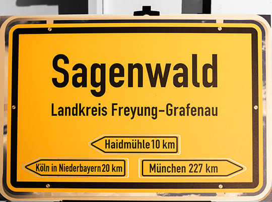 Das gelbe Ortsschild Sagenwalds, darauf steht: Sagenwald Landkreis Freyung-Grafenau