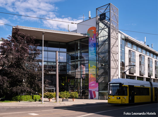 Außenansicht des NYX Hotels Berlin Köpenick by Leonardo Hotels mit vorbeifahrender Straßenbahn