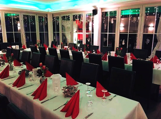 Weihnachtliche Dekoration, rote Servietten, weiße Tischdecken und schwarze Stühle. mit großen Panorama-Fenstern.