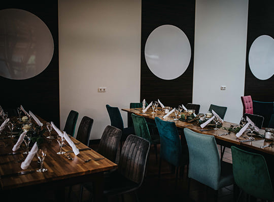 Moderne Möbelausstattung im Speisesaal mit schwarz-weiß gestrichener Wand und edler Holzstischen.