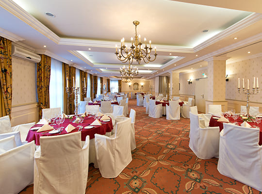 Großer sowie langer Speisesaal mit vielen liebevoll dekorierten Tischen für ein schönes Event angerichtet.