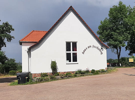 Blick vom Hof auf die moderne, weiß gestrichene Gaststätte