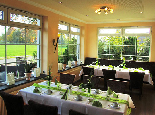 Weiß und grün dekorierter Tisch in modernem Ambiente und Ausblick ins Grüne