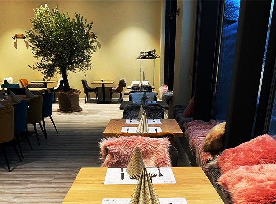 Einladend bequemer Restaurant-Bereich mit großen Panorama-Fenstern und flauschigen Kissen.