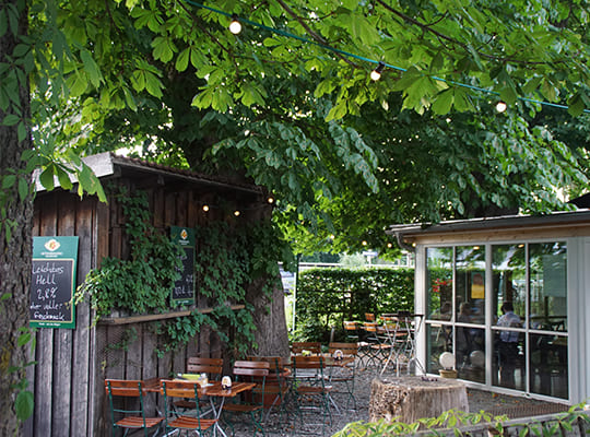 Toller, naturnaher Außenbereich mit vielen Sitzmöglichkeiten direkt am Restaurant unter einem Baum