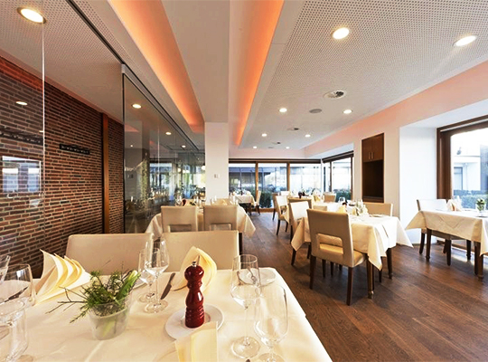 Lichtdurchfluteter Restaurantbereich mit heller Tischdekoration und schöner Steinklinger-Wand