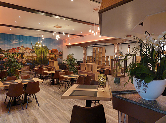 Liebevoll gestalteter Restaurant Bereich rund um die Restaurant-Bar. Mit bequemen Sitzgelegenheiten und einem riesigen Wandbild der Stadt Lüneburg.