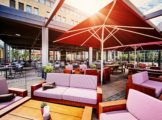 Stilvoll und bequem eingerichtete Terrasse, mit modernen Möbeln, einem Sonnenschirm und strahlendem Sonnenschein.