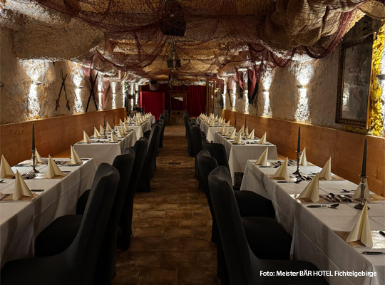 stimmungsvoll beleuchteter Gewölbekeller mit festlich gedeckten Tischen