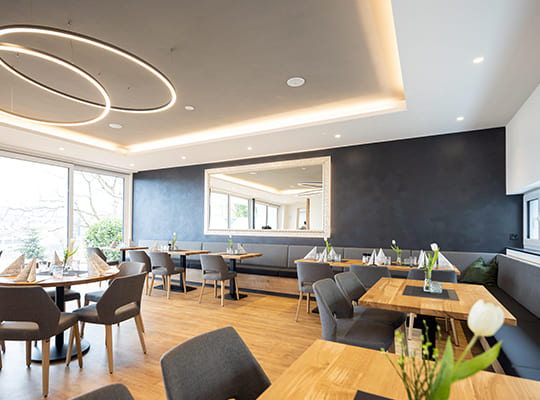 Renovierter Speisesaal mit schönen Deckenleuchten, hellen Panoramafenstern und bequemen Sitzmöglichkeiten.