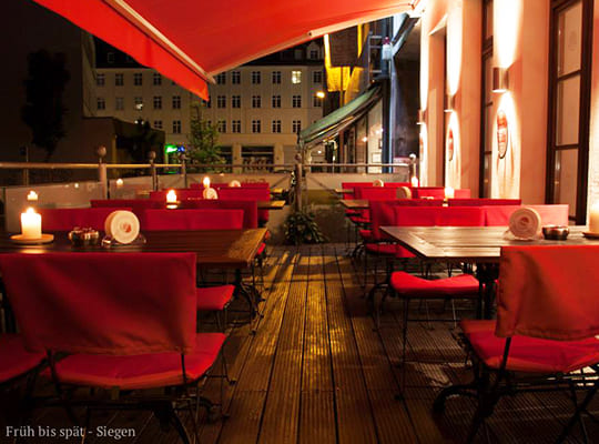 Schöner Terrassenbereich mit vielen Bequemen Sitzmöbeln und heller Beleuchtung in der Nacht.