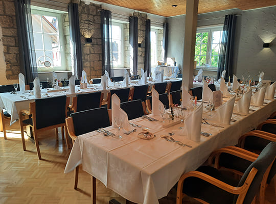 Lichtdurchflutete große Fenster im Restaurantsaal mit langen Tischtafeln angerichtet für das Kriminal Dinner.