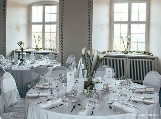 Schön dekorierter Speisesaal mit runden Tischen in weißen Laken für das Krimidinner