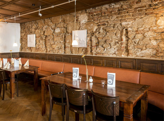Speißesaal des Restaurants mit Möbeln aus Holz und einer Steinwand