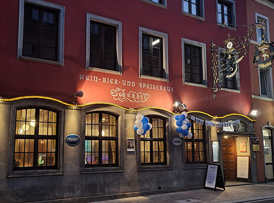 Schönes Restaurant-Gebäude bestehend aus grauer Mauer inkl. Fenster und roter Fassade darüber.