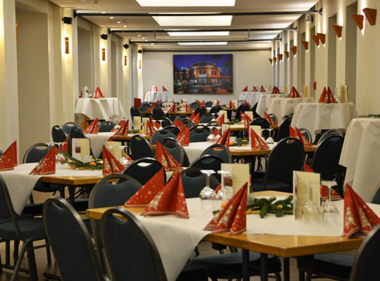 Großer Speisesaal festlich dekoriert mit vielen Sitzmöglichkeiten und schöner Tischdekoration.