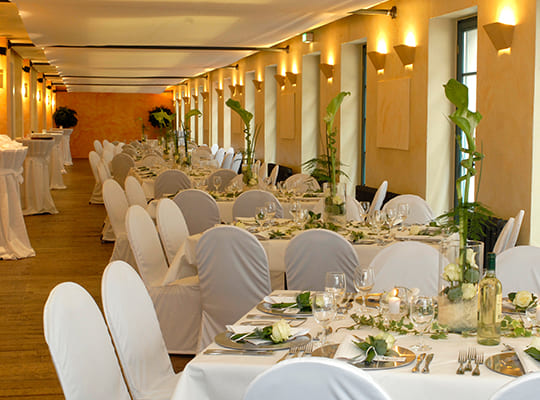 Festlich dekorierter Speisesaal mit weißen Hussen gestaltet und wunderschöner Tischdekoration.