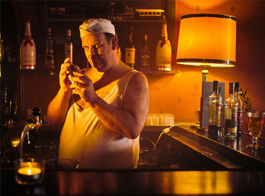 Düstere Kneipe mit Barkeeper, Alkoholflaschen im Hintergrund