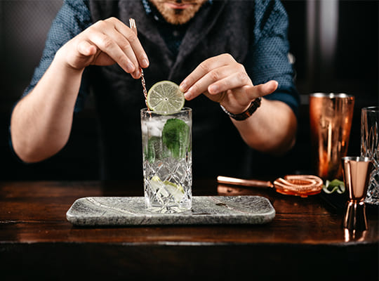 Ein Barkeeper mixt einen leckeren, schmackhaften Gin-Cocktail zusammen
